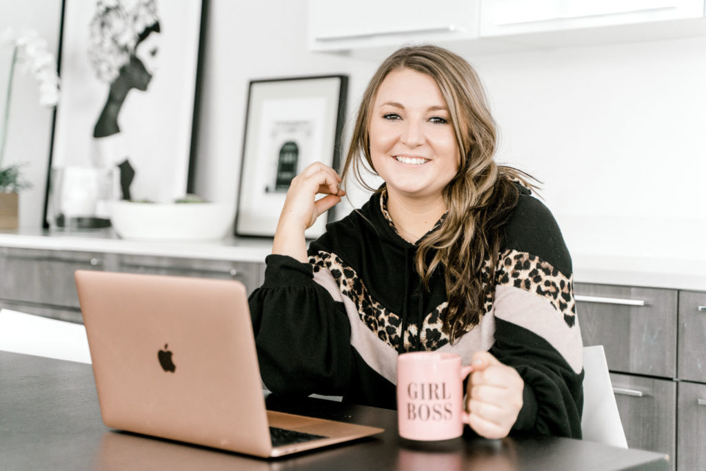 Woman working on laptop with girl boss coffee mug